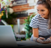 Woman looking at computer holding phone