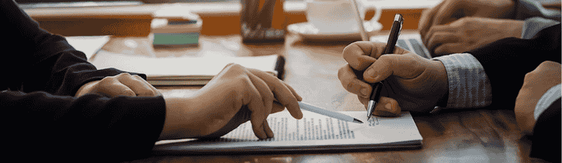 two hands signing a document