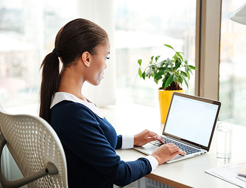 Young woman at the desk using a laptop.