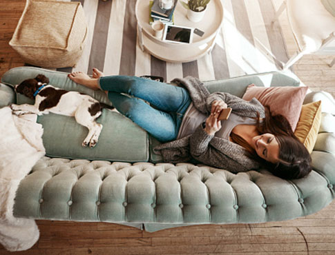 Lady on couch using her smartphone to look at the news