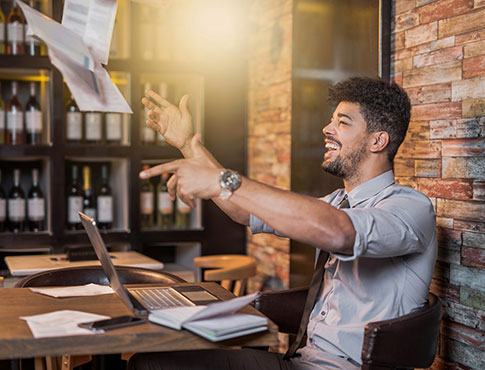 A man in an office throwing papers in the air while smiling