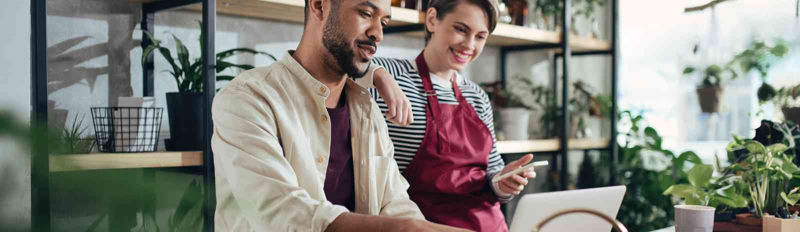 A man and a woman in front of a laptop in a flower shop.